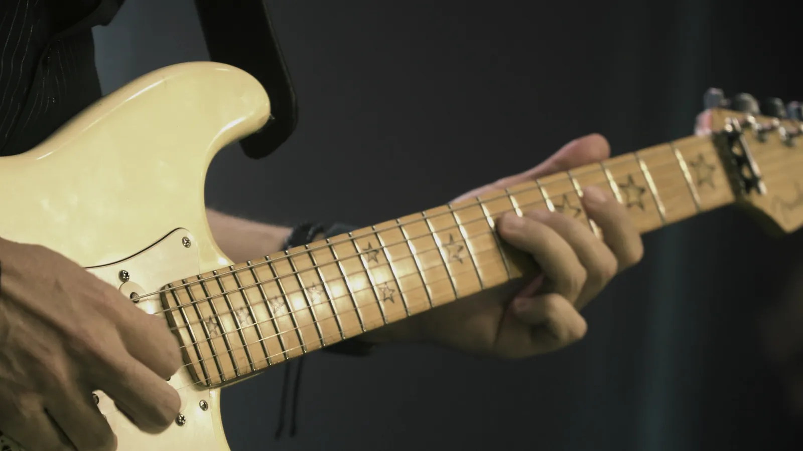 Close das mãos de um guitarrista tocando durante um show